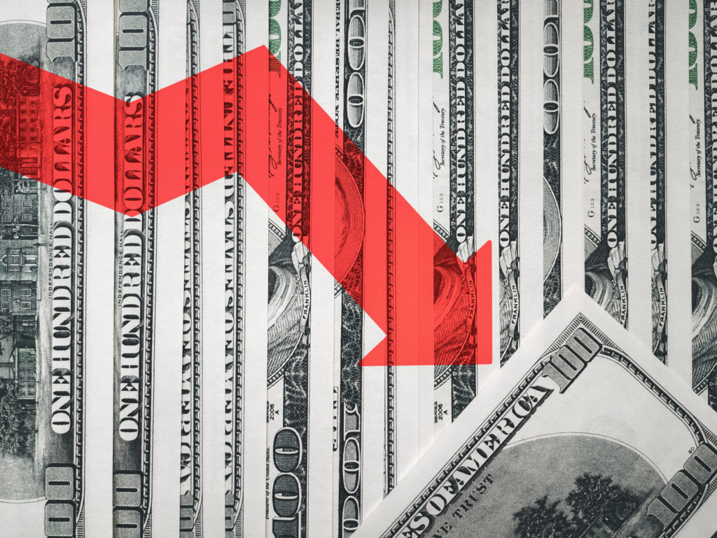The light red arrow icon on a background of money. The concept of changing course of US dollar on the market. Devaluation, collapse, stagnation of the economy.