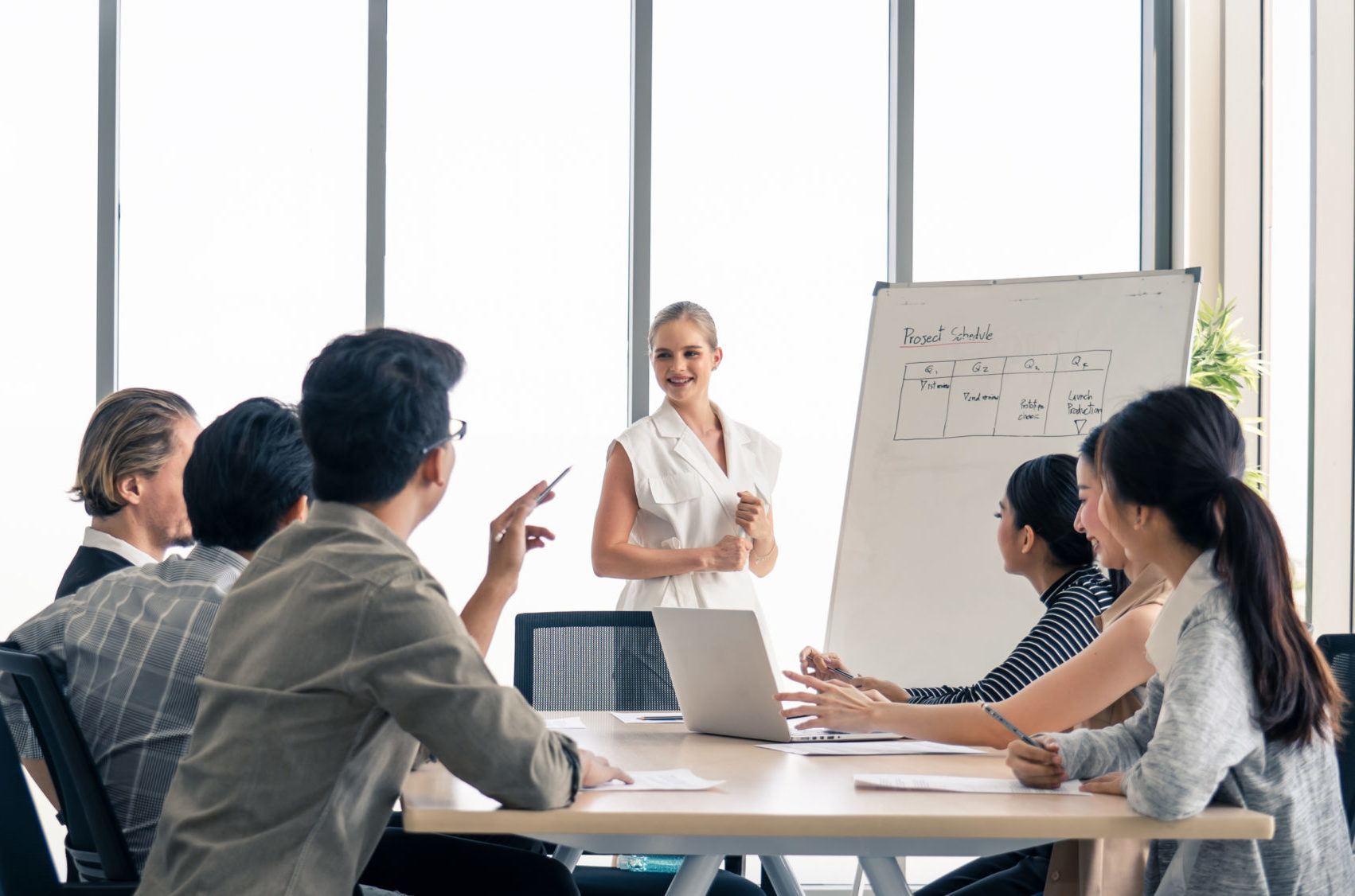 Team of workers in a room with a whiteboard talking aBOU