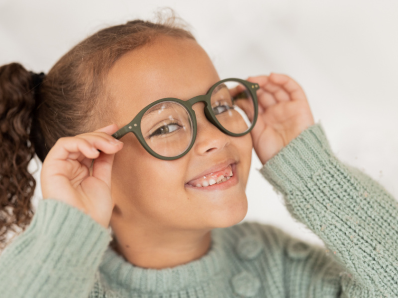 Little Black girl putting on her new glasses and smiling